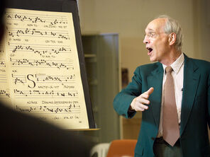 Bill Mahrt looks to the left, where a Gregorian chant is written out